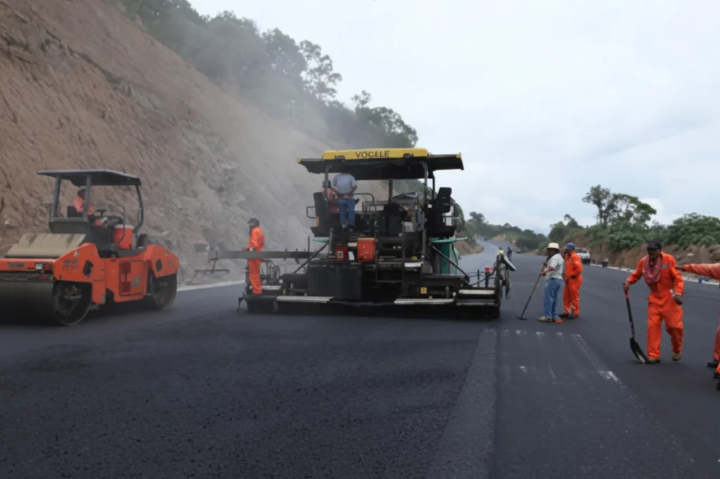 Cuadrilla de camineros aplicando mezcla asfáltica en conmemoración del Día del Caminero, símbolo de la ingeniería que mantiene la movilidad nacional.
