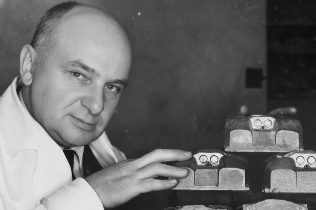 Inventor del ojo de gato vial mostrando los primeros modelos de marcadores de carretera utilizados para mejorar la visibilidad y la seguridad en la conducción.